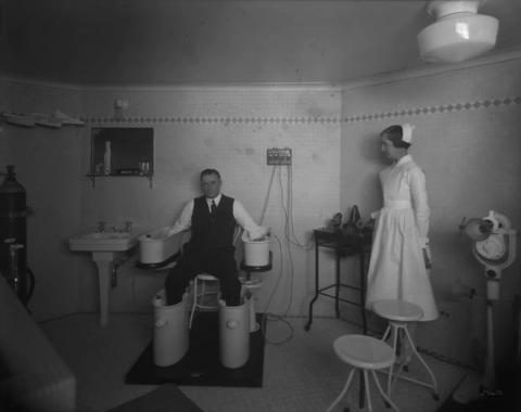 A man immerses his hands and feet in a Schnee Bath — which was used to treat ailments such as rheumatoid arthritis — in this 1931 photo taken inside the Château Laurier's 'special treatment room.' (Library and Archives Canada)
